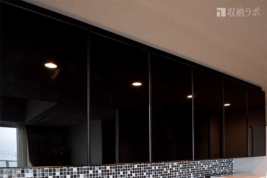 オーダーメイドの食器棚の吊り戸棚は、ブラックのスモークガラスを採用。